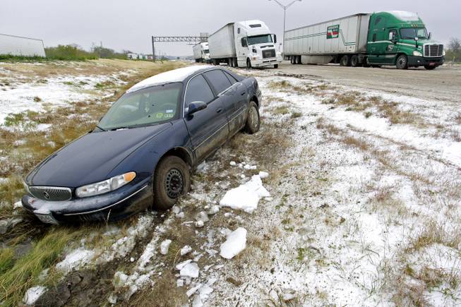 A car that slid off of the road sits abandoned on I-20 (westbound) near Winscott Rd. in Benbrook. Cold and ice remained in Fort Worth Sunday, Dec. 8, 2013, with roads especially treacherous in the the morning hours before temperatures rose. (AP Photo/Fort Worth Star-Telegram, Paul Moseley)